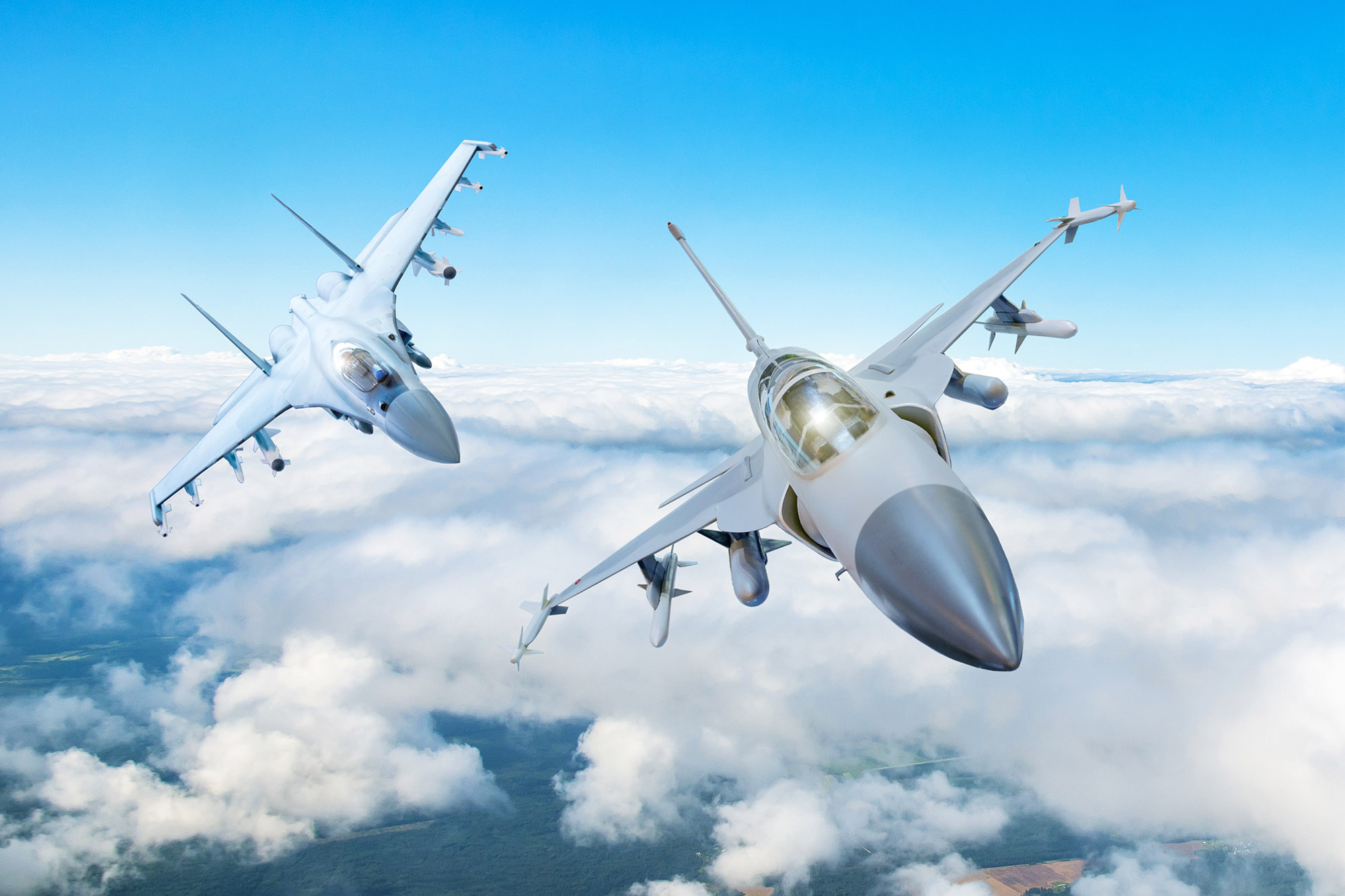 Pair of combat fighter jet on a military mission with weapons - rockets, bombs, weapons on wings flies high in the sky above the clouds.